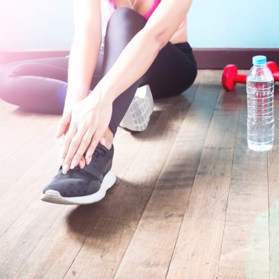 Fitness female in black pants and sneaker stretching after workout with copy space